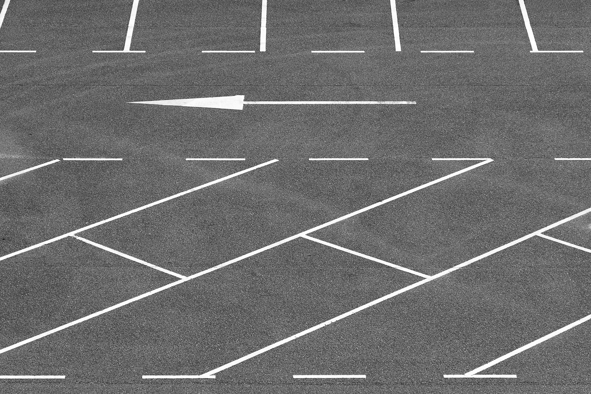 A minimalist view of an empty parking lot with directional arrow and parking lines.